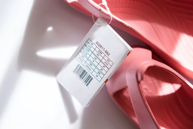Detailed shot of pink sandals showing size tag and barcode for retail display. Varianten, Grössen und Lagerbestand im Produktkatalog